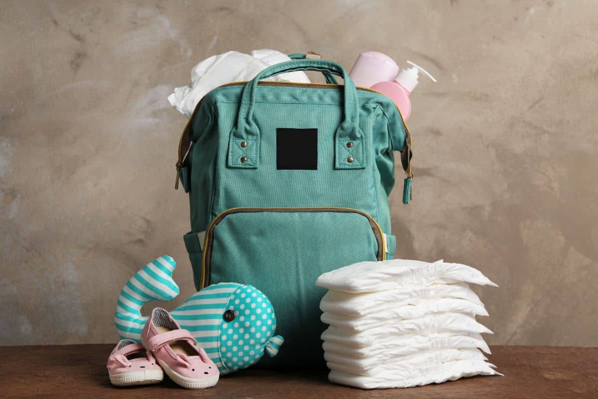 Image showing a plush toy with some diapers and a blue backpack that can be among the 6 Best Travel Diaper Bags