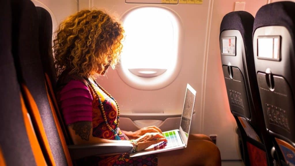 How Many Electronics Can You Bring On A Plane_Woman with laptop on plane