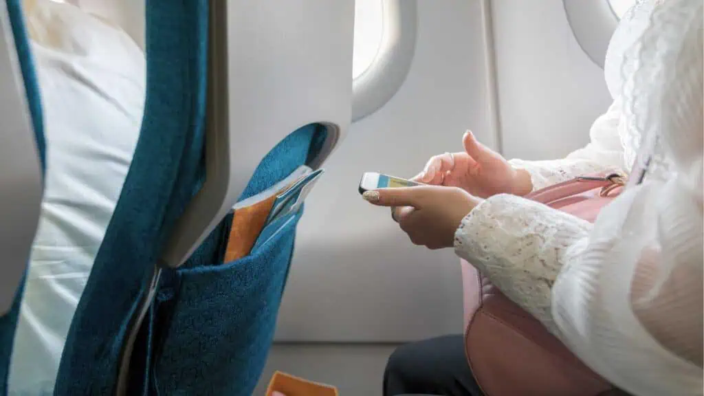 A femaile passenger using her smartphone on a flight